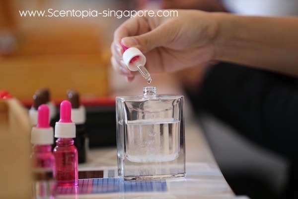hand putting essential oil in perfume bottle at workshop